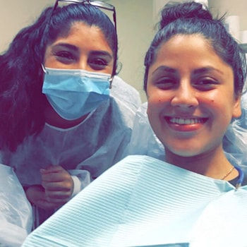Our dental assistant wearing a dental mask and smiling with one of our patients